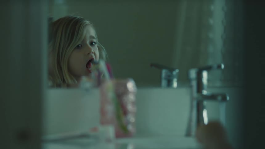 Child brushing teeth in front of the bathroom mirror