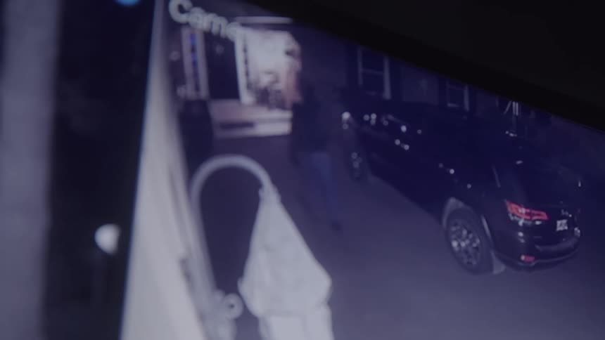 A person walks up a driveway to the front door of a house