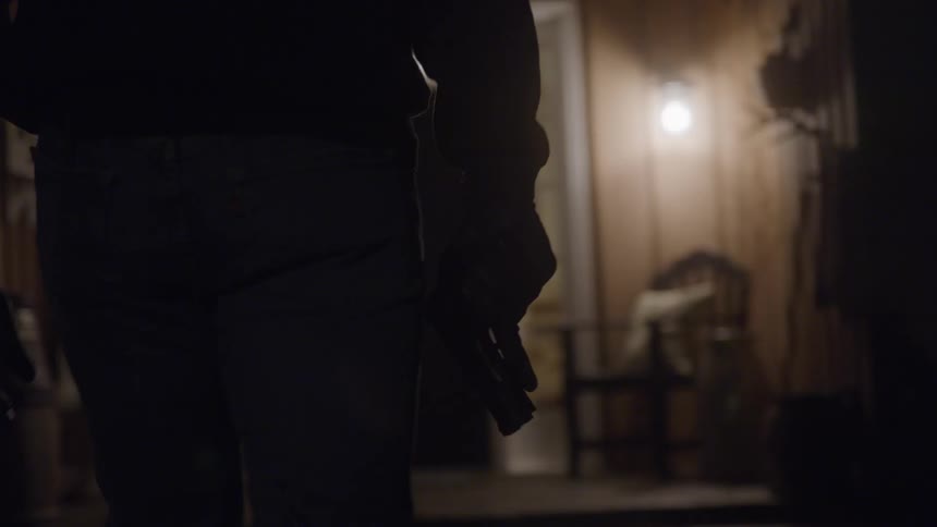 Person in jeans holding a gun in hand in a dark setting