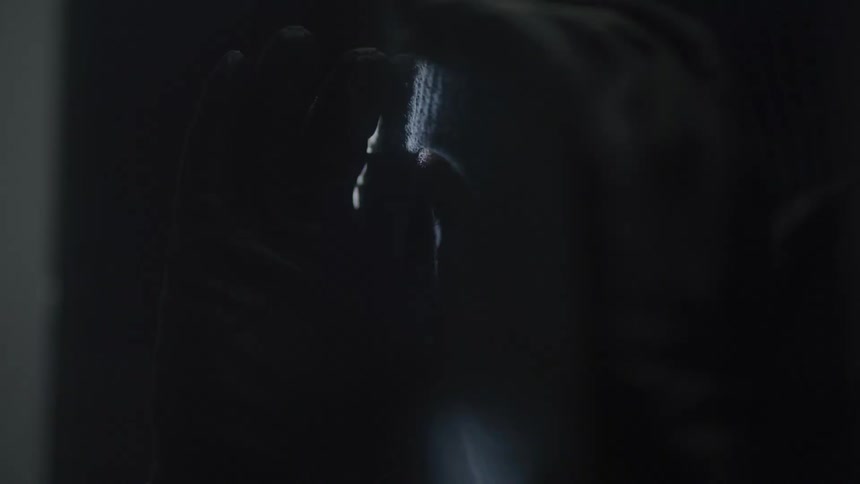 Person wearing a hood and dark balaclava in a dimly lit environment