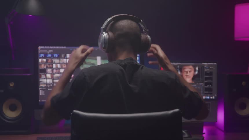 A man puts his headphones on at his desk