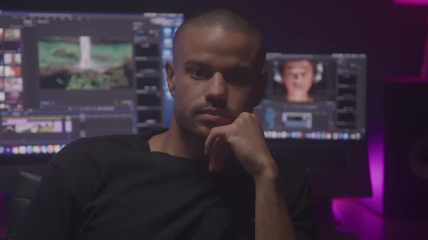 The man sits in front of his computers with his back turned