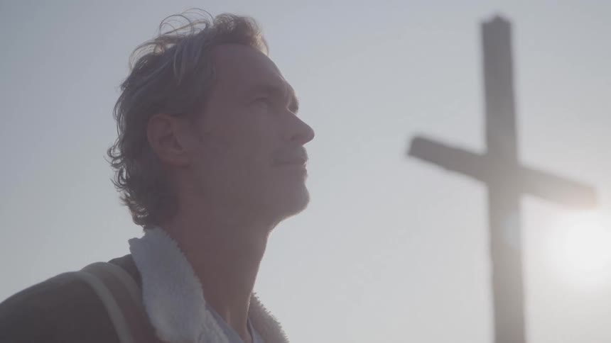 A middleaged man wearing a jacket standing outdoors under the sun