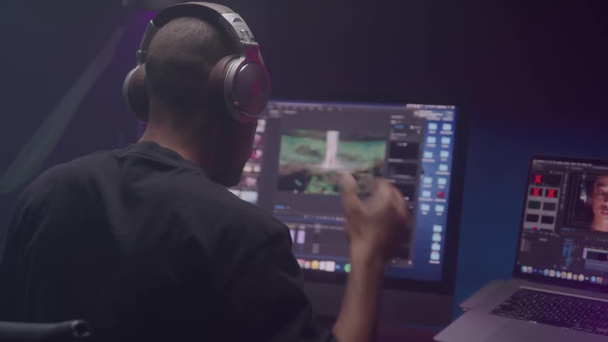 A man puts on headphones as he moves closer to his computer