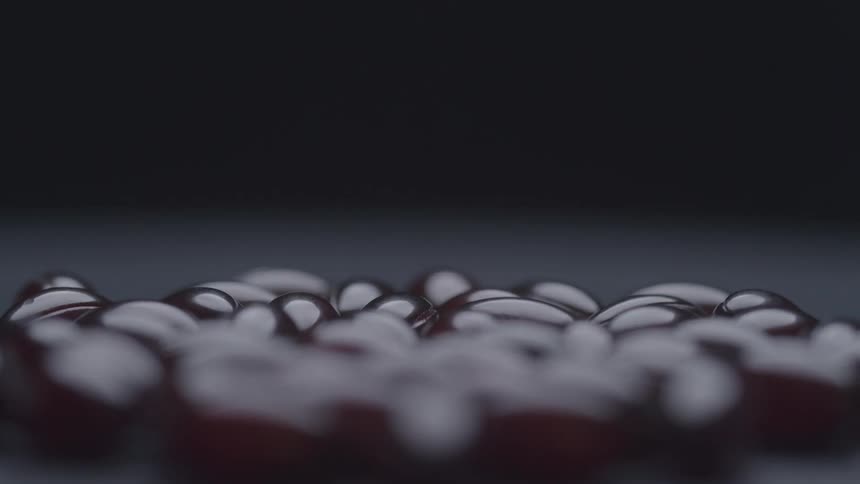A pile of small translucent dark red capsules