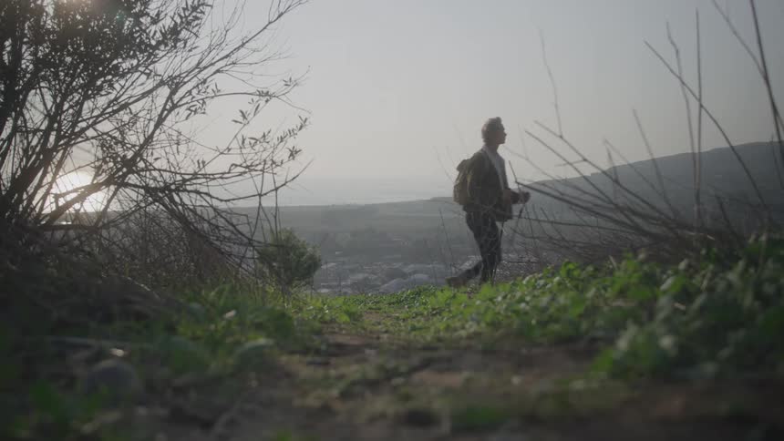 The man hikes on the mountain through heavy fog