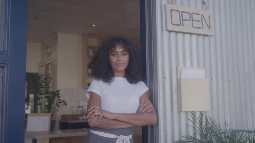 Close up of a young black woman posing in front of the entrance of a restaurant during daytime
