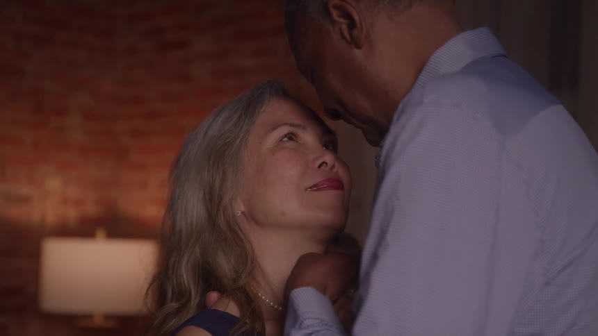 An older couple gazes lovingly at each other as they embrace