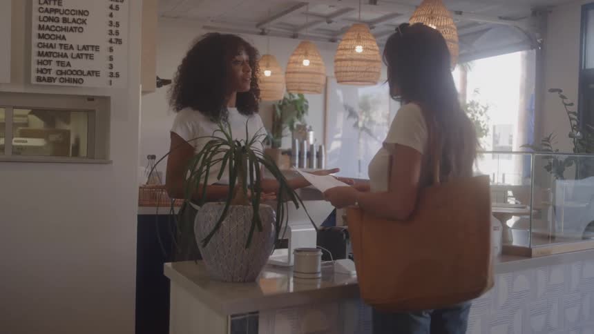 A woman talks with a customer as she pays