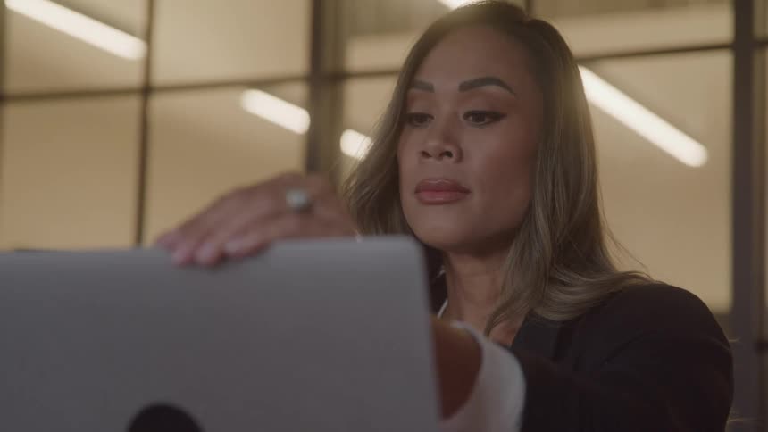 A woman sitting in an office opens her laptop