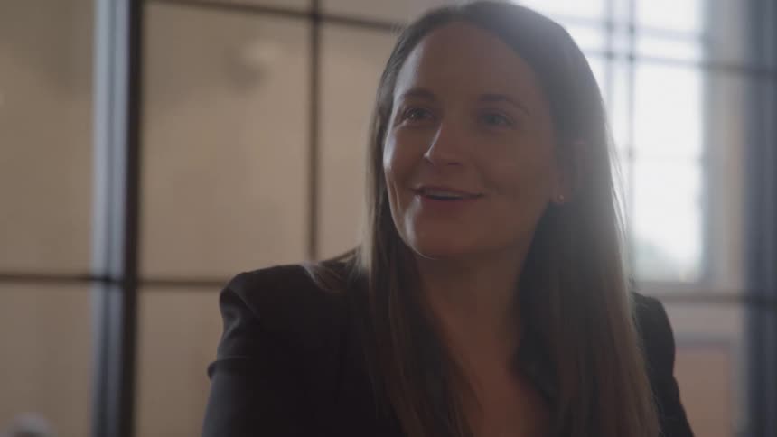 A woman smiles in an office as she talks to another woman