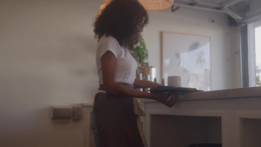 A shot of a waitress with curly hair going to serve a customer at a cafe