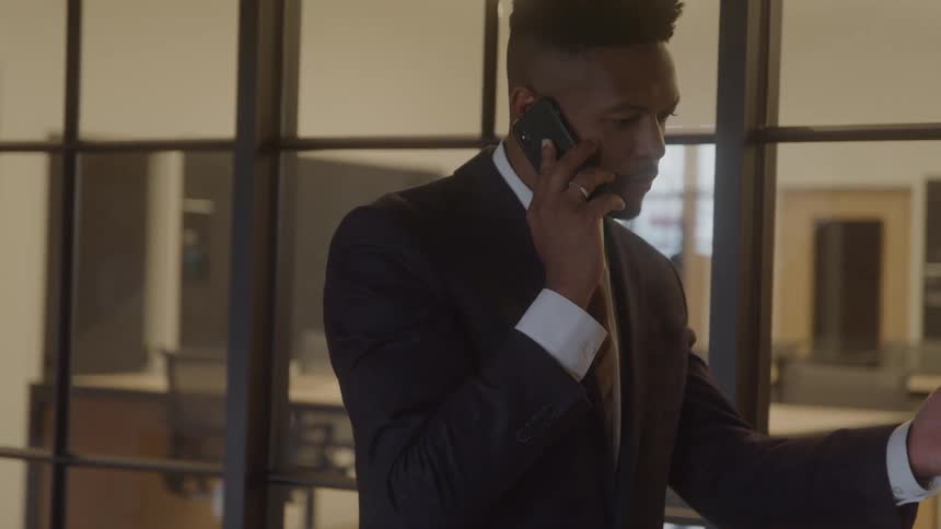 The man is talking on his cell phone in the office