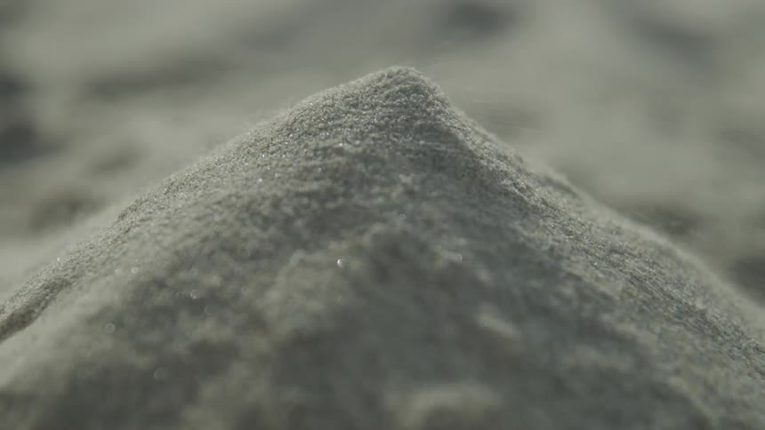 Wind blows away grains of sand from a pile