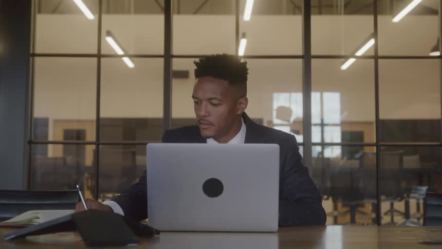 The man is writing notes at the desk