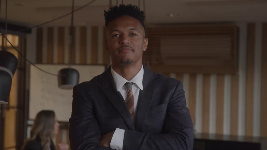The man folds his arms while smiling in the office