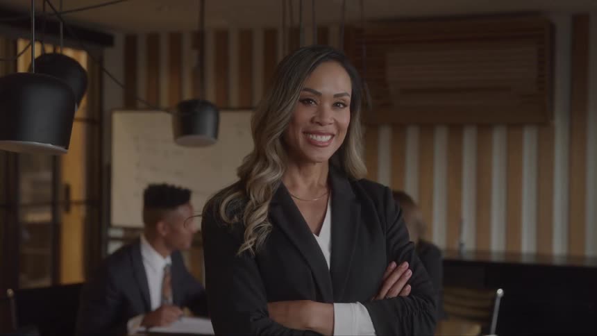 The woman folds her arms and smiles in the office