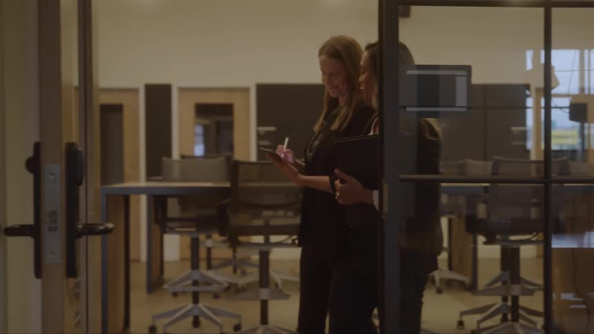 Two women walk through the office together