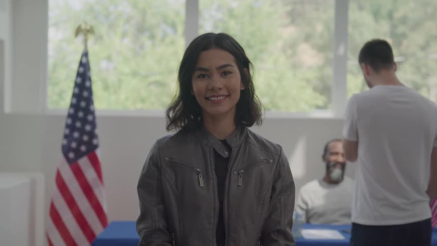A woman is standing and smiling in the hall