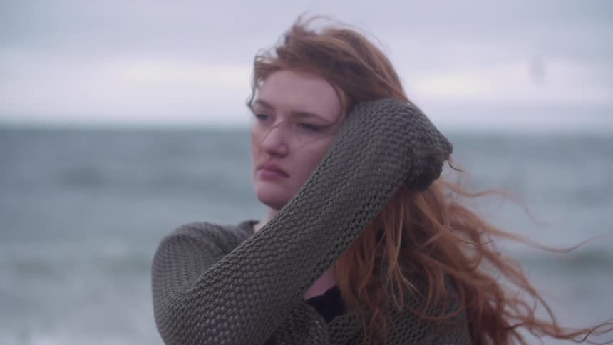 A woman stands on a windy beach