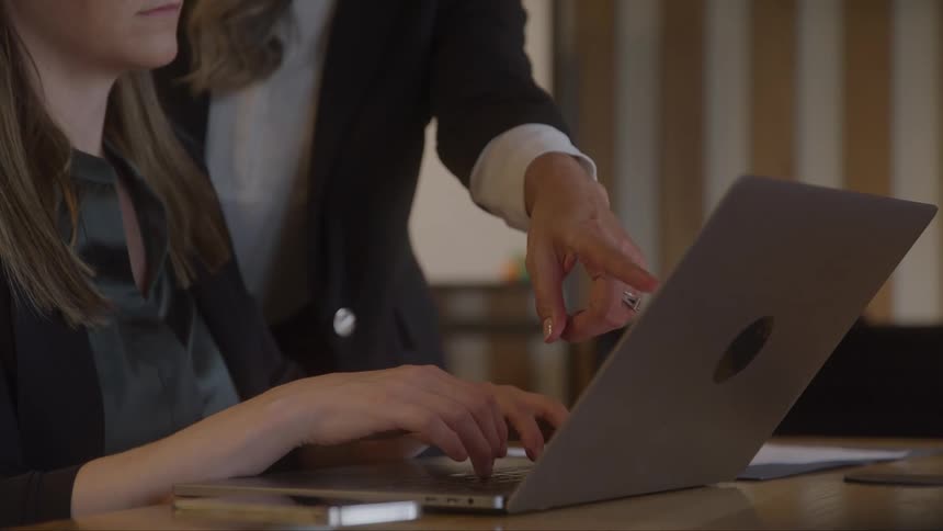 A woman is typing on the laptop at the desk