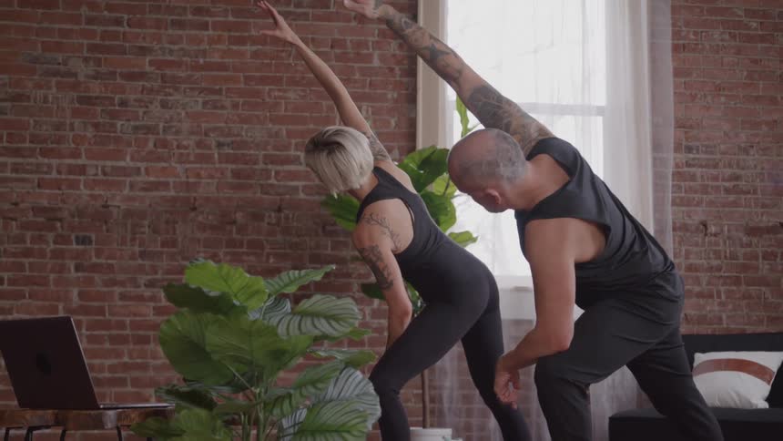 Two people do yoga together at home