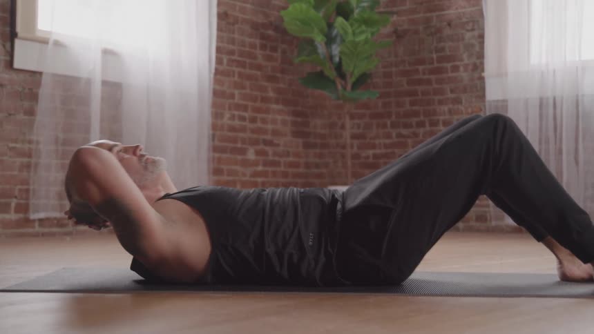 Man lying on a yoga mat doing an abdominal exercise