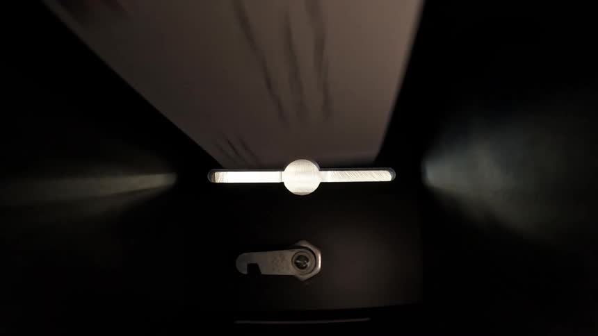 A white paper bill with black writing falls through a slit and into a dark box