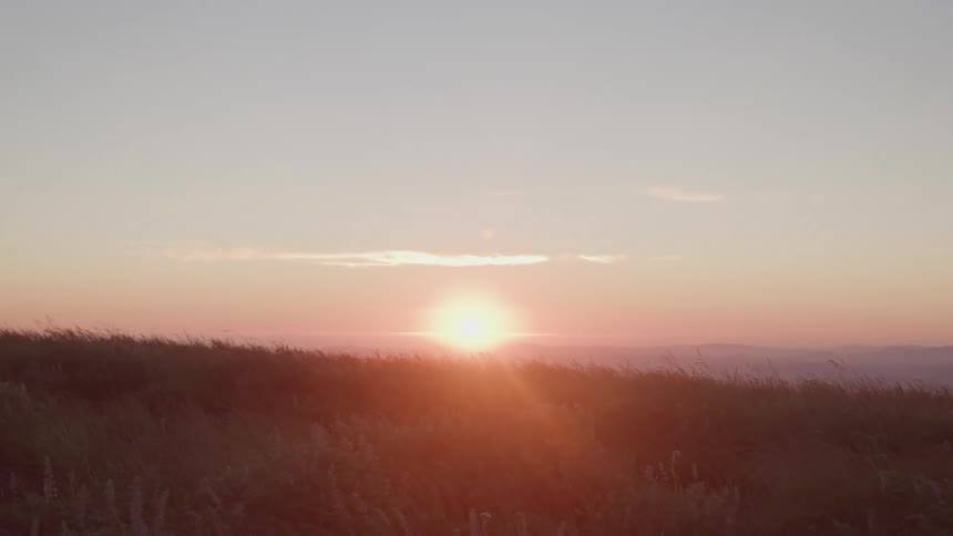 Sun setting behind an open field with the horizon in the background