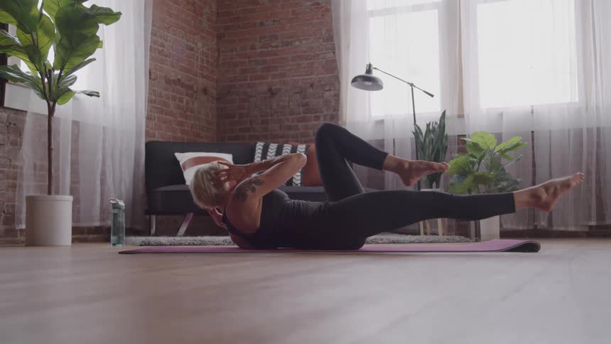 A young woman working out on a floor mat in a room during daytime