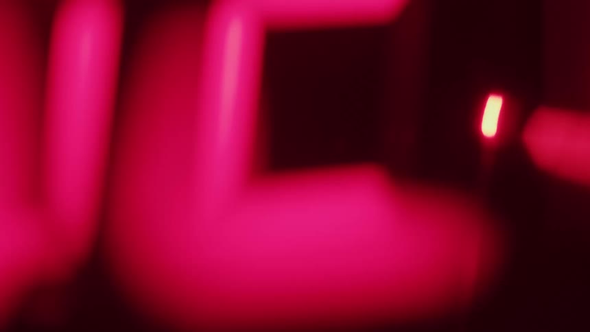 Red numbers of a digital clock seen in blurred closeup