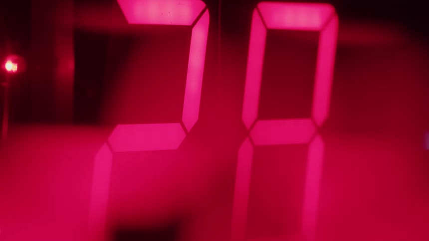 An extreme closeup on a digital display shows red numbers rapidly counting down to zero on a timer or clock