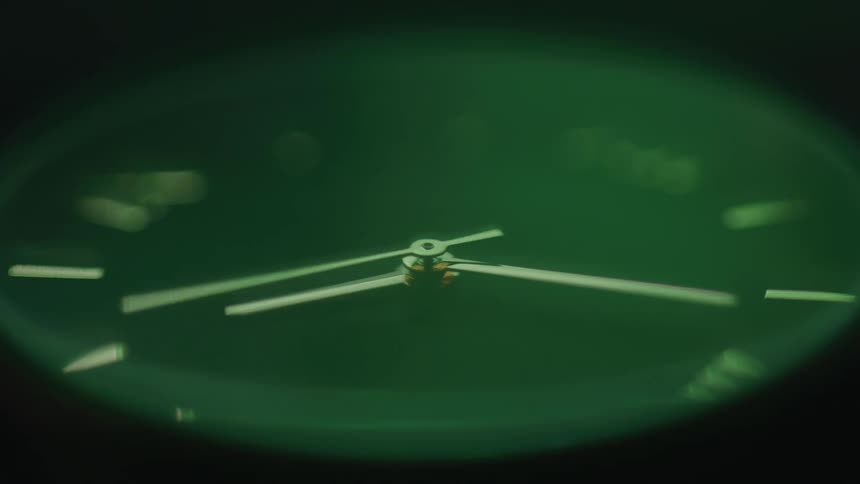 Extreme close up of a working green analogue watch dial