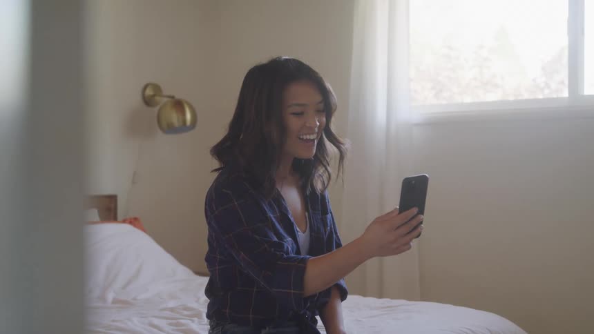 The woman smiles and waves at her phone