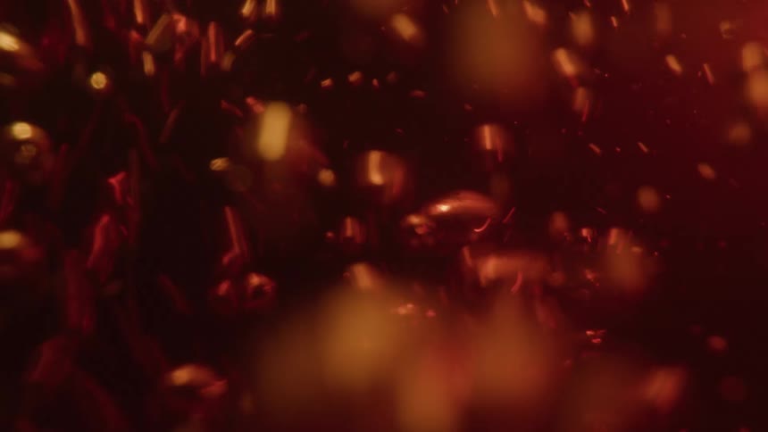In a turbulent extreme closeup a flurry of bubbles is forced downwards through a dark ambercolored liquid as it is poured before they begin to float back upwards