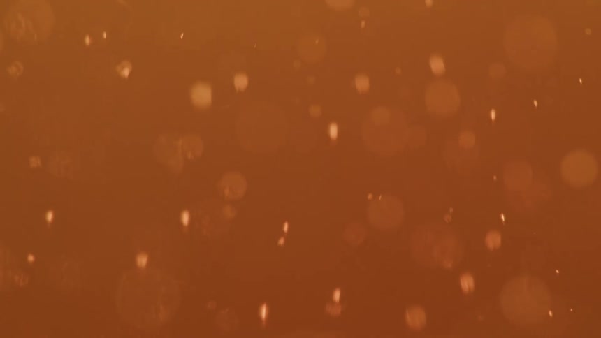 Outoffocus bubbles slowly rise through a hazy orangecolored liquid in a closeup slowmotion shot