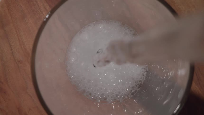 A carbonated beverage is quickly poured into a drinking glass