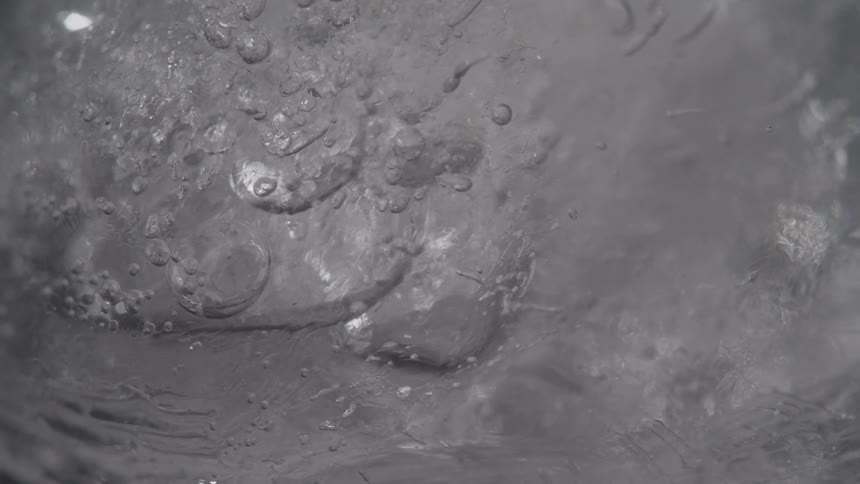 A piece of ice is slowly rotated and trapped bubbles are frozen beneath its surface