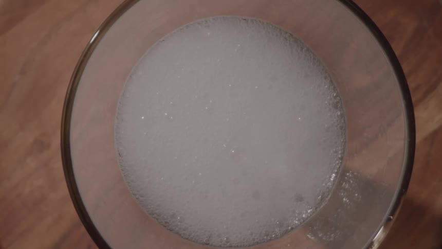 Bubbles on top of a carbonated beverage in a drinking glass are all popping