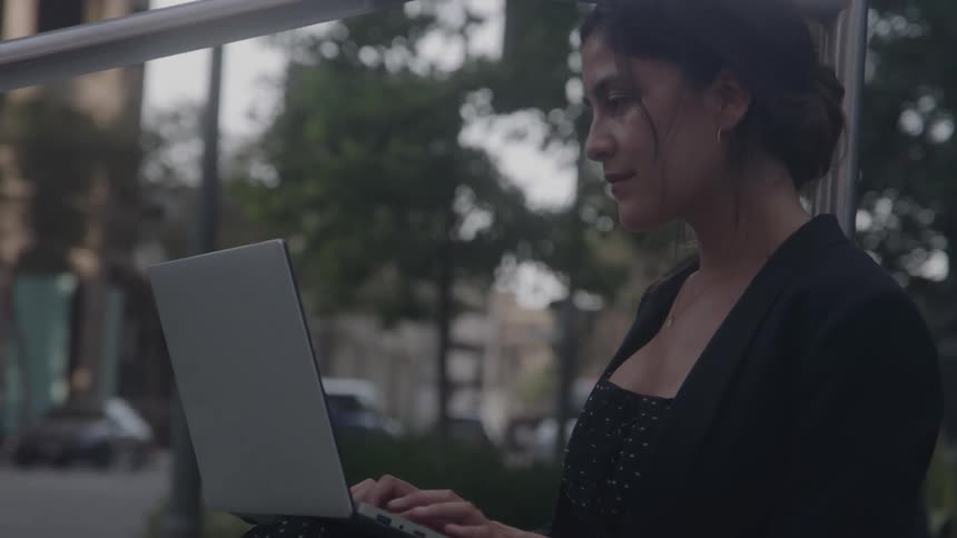 Woman using a laptop outdoors in an urban area