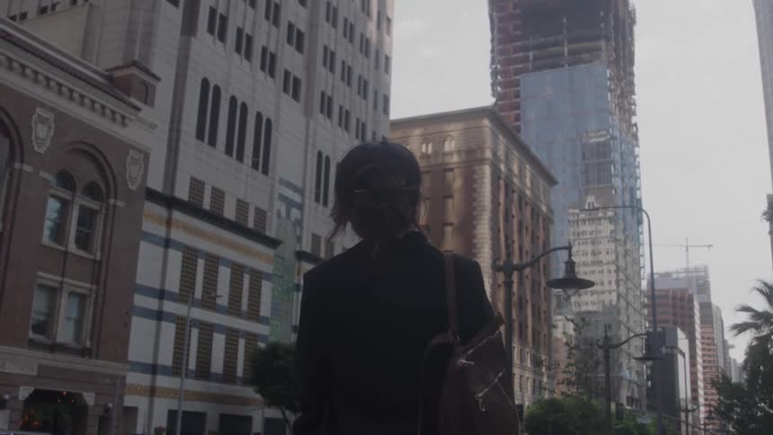 A woman is standing in a city looking at the buildings