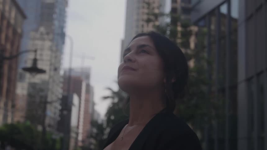 Close up portrait of a young woman standing on a metropolitan street contemplatively during daytime