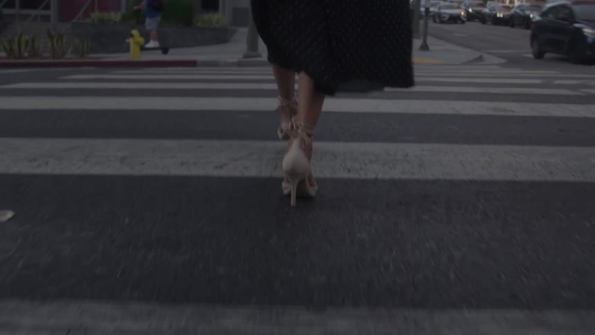 Woman in high heels crossing a crosswalk in an urban area