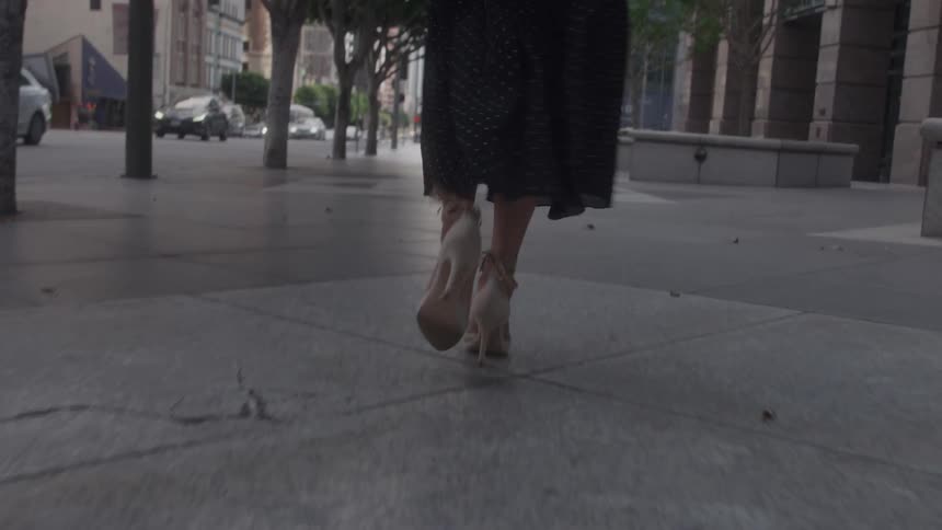 Steps of a person in high heels walking on an urban sidewalk