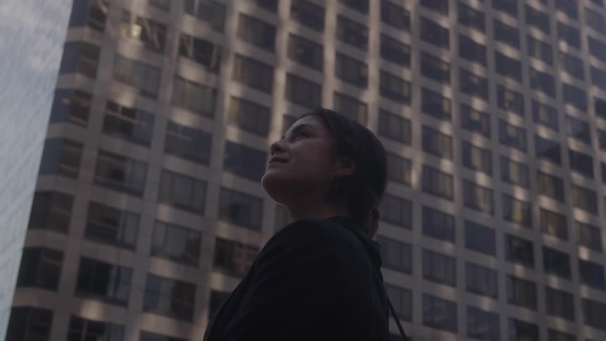 Woman looking upward among tall buildings in the city center