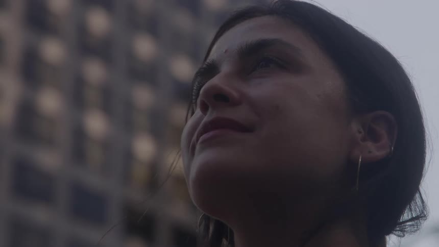 Woman with a serene expression looking upward in an urban setting