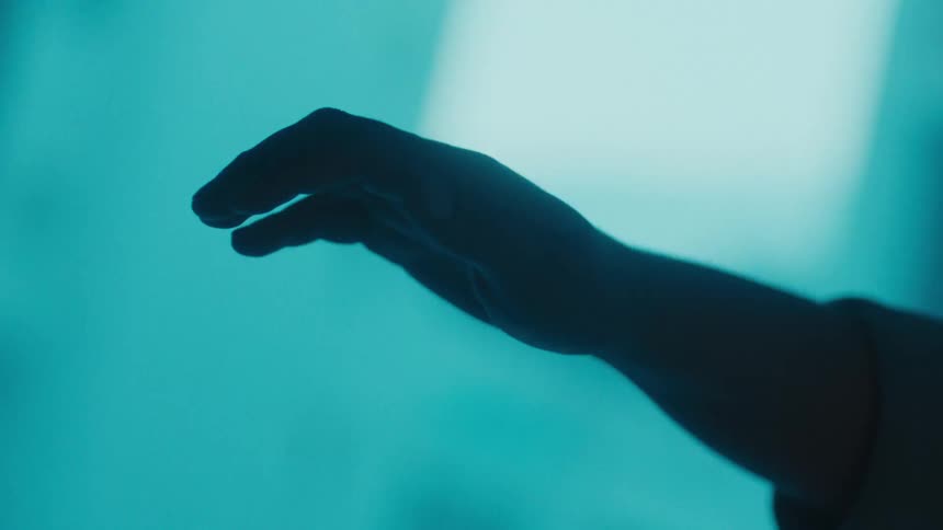 A silhouetted hand is raised against a blue background