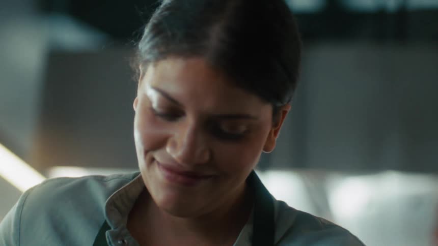 Woman smiles subtly while looking down indoors