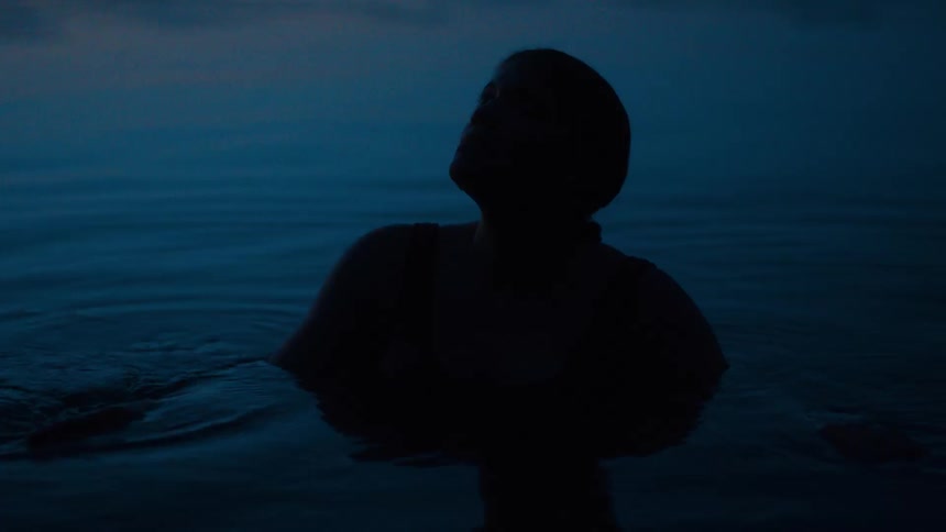 The silhouette of a person on the water their head tilted upwards against a dark nocturnal backdrop