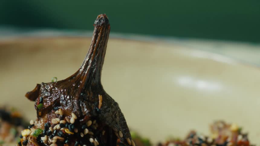 Closeup of roasted baby eggplant garnished with spices on a plate
